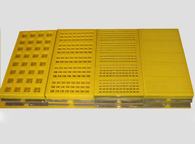 Four types of yellow modular polyurethane screen meshes with different opening sizes and hooks.